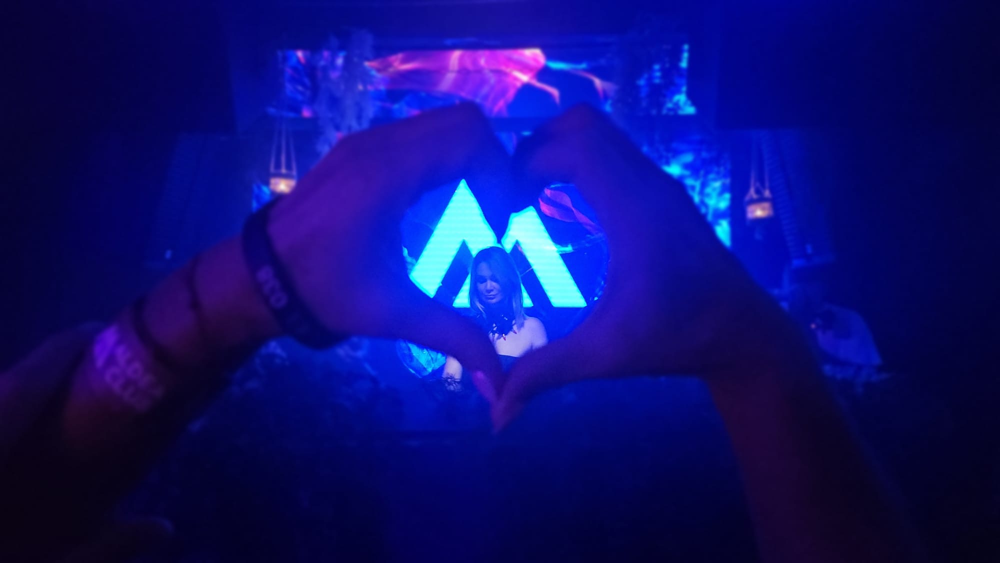 Hands forming a heart over the glowing MELODICA M logo